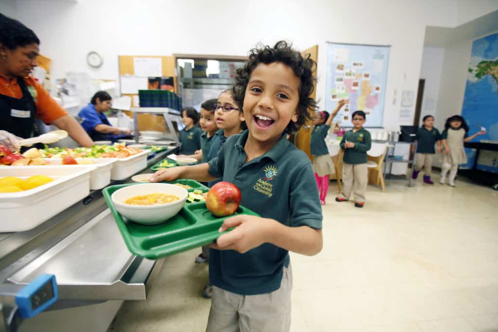 Jayden Ochoa, a first grader at the Academy of Global Citizenship in Chicago, smiles as he takes his full tray of food to his seat in the school's cafeteria Monday, May 13, 2013. | Photo by J.Geil