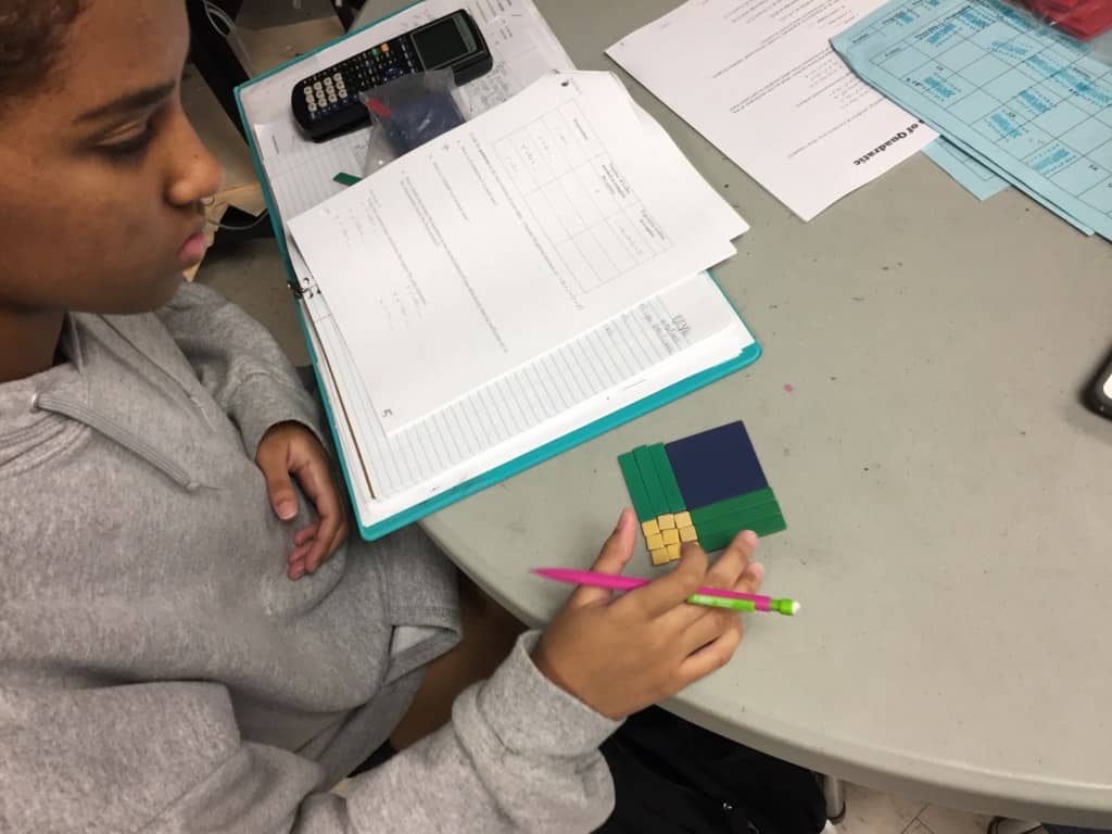Students in Mr. Ferguson's ninth grade Honors Math 2 class discover the process of completing the square using an area model with algebra tiles.