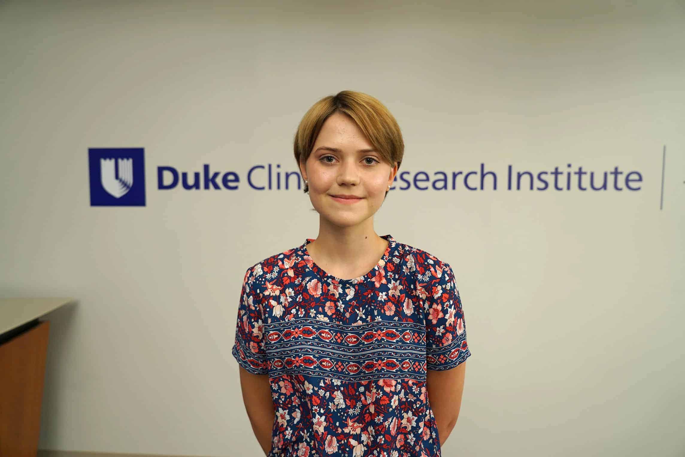 Cordelia stands in front of Duke signage