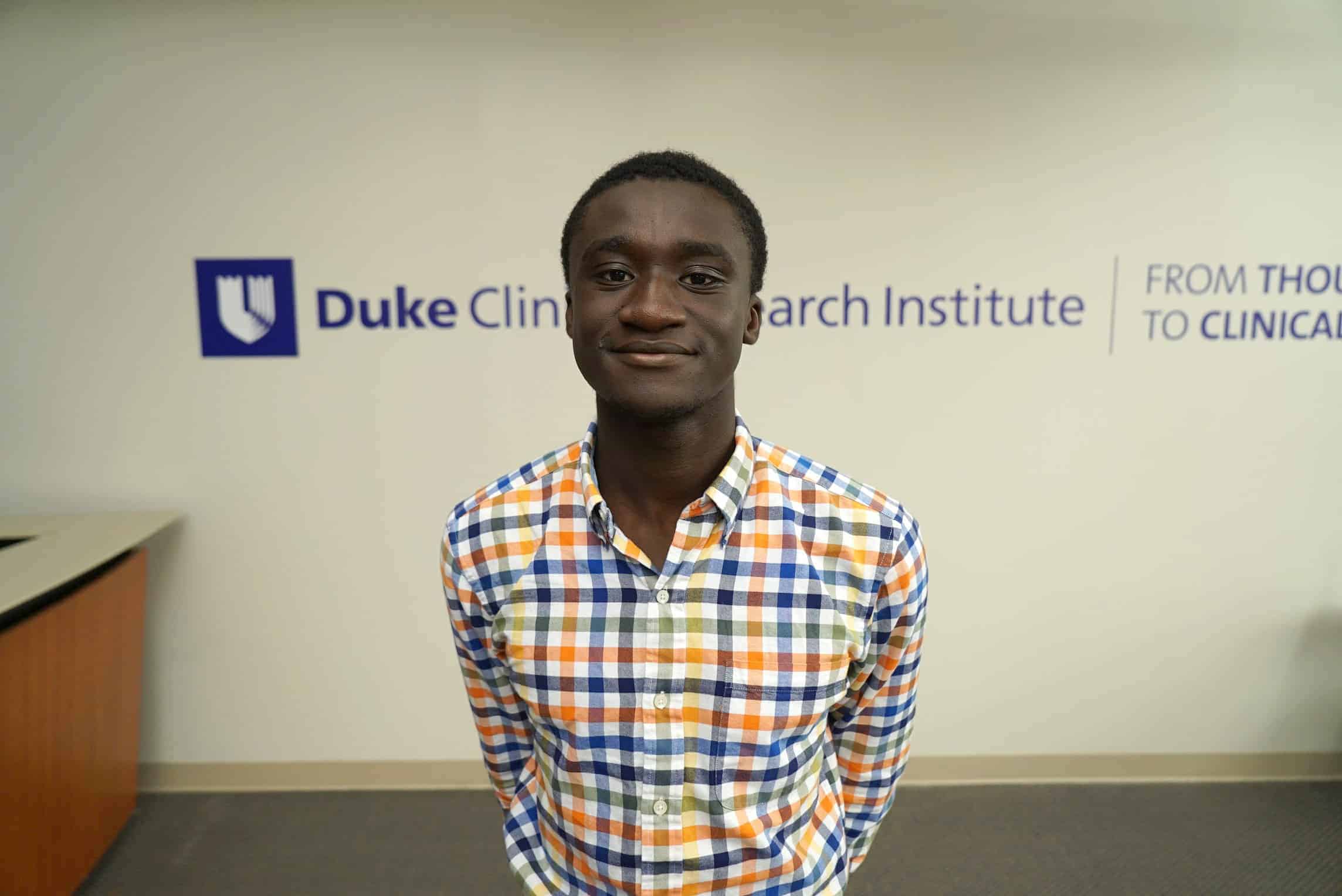 Samuel stands in front of Duke signage