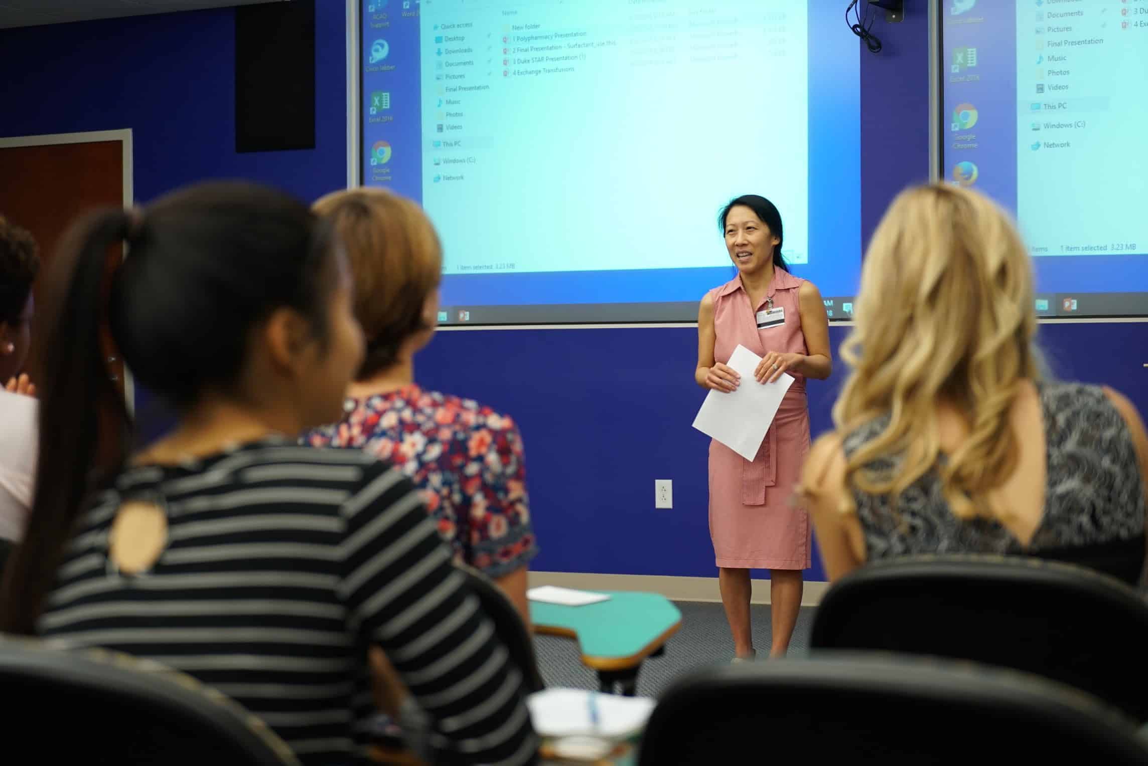 Dr. Chu speaking in front of students in desks