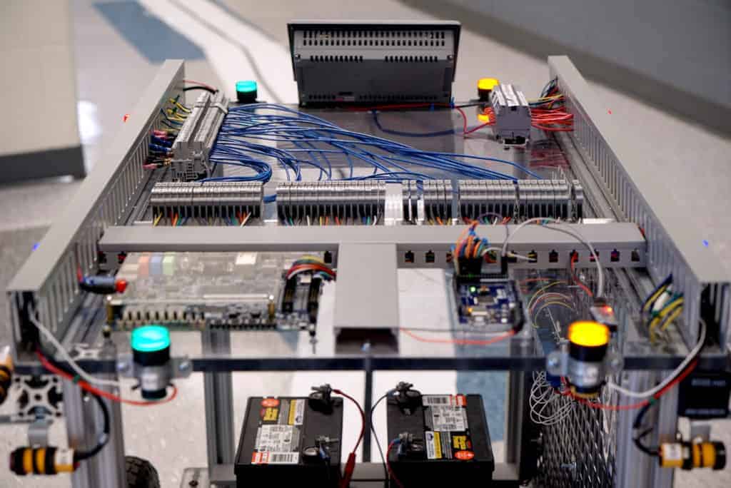A four-wheeled cart with many circuit boards and wires