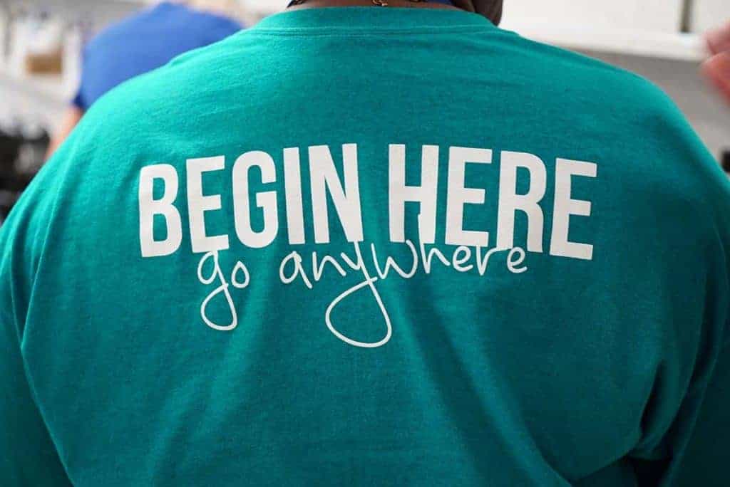 A student wears a t-shirt bearing the slogan "Begin here, go anywhere."