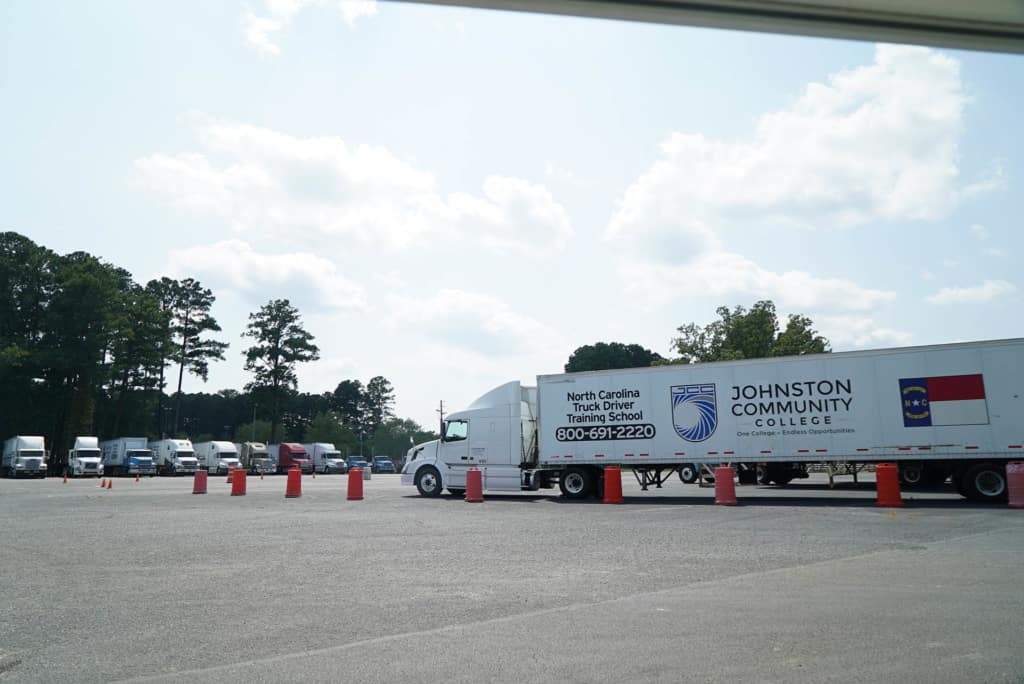 A big rig truck with truck driving school ad on side 