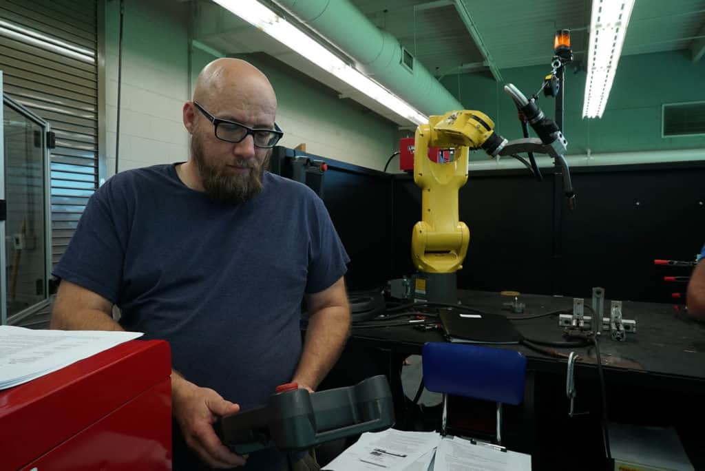 an instructor with remote control and robotic welding arm