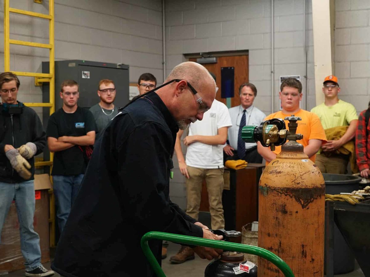 A professor unscrews gas tank in front of class