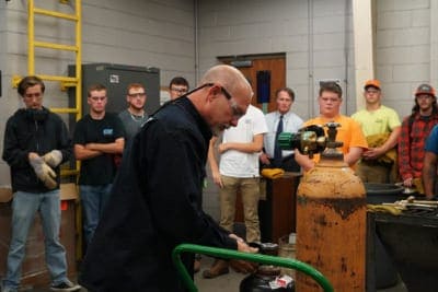 A professor unscrews gas tank in front of class