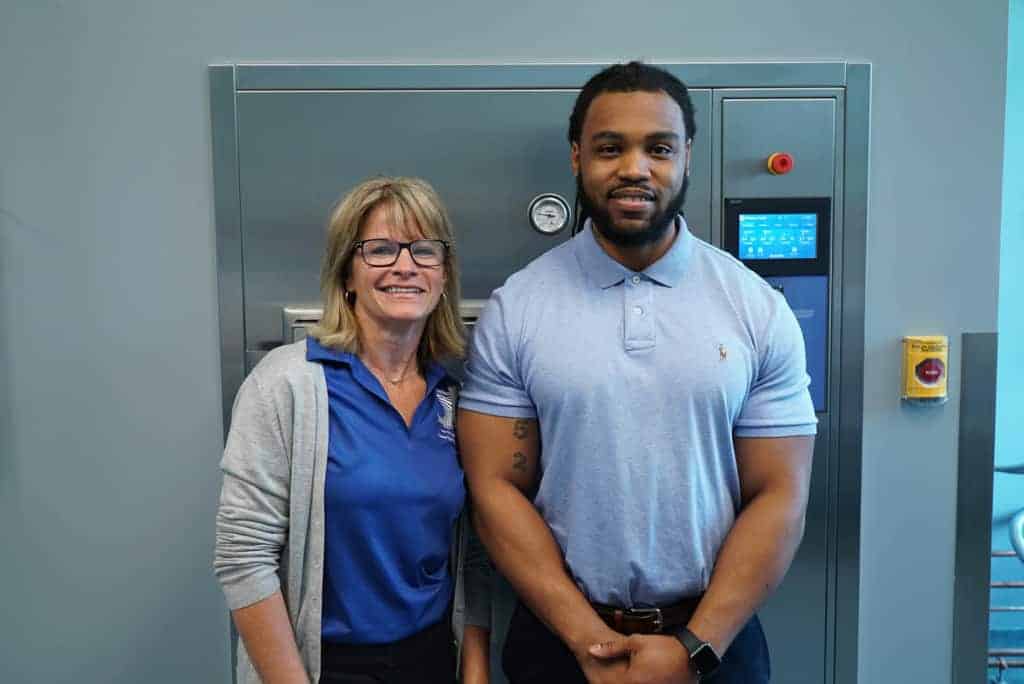 an instructor and student stand in front of machinery