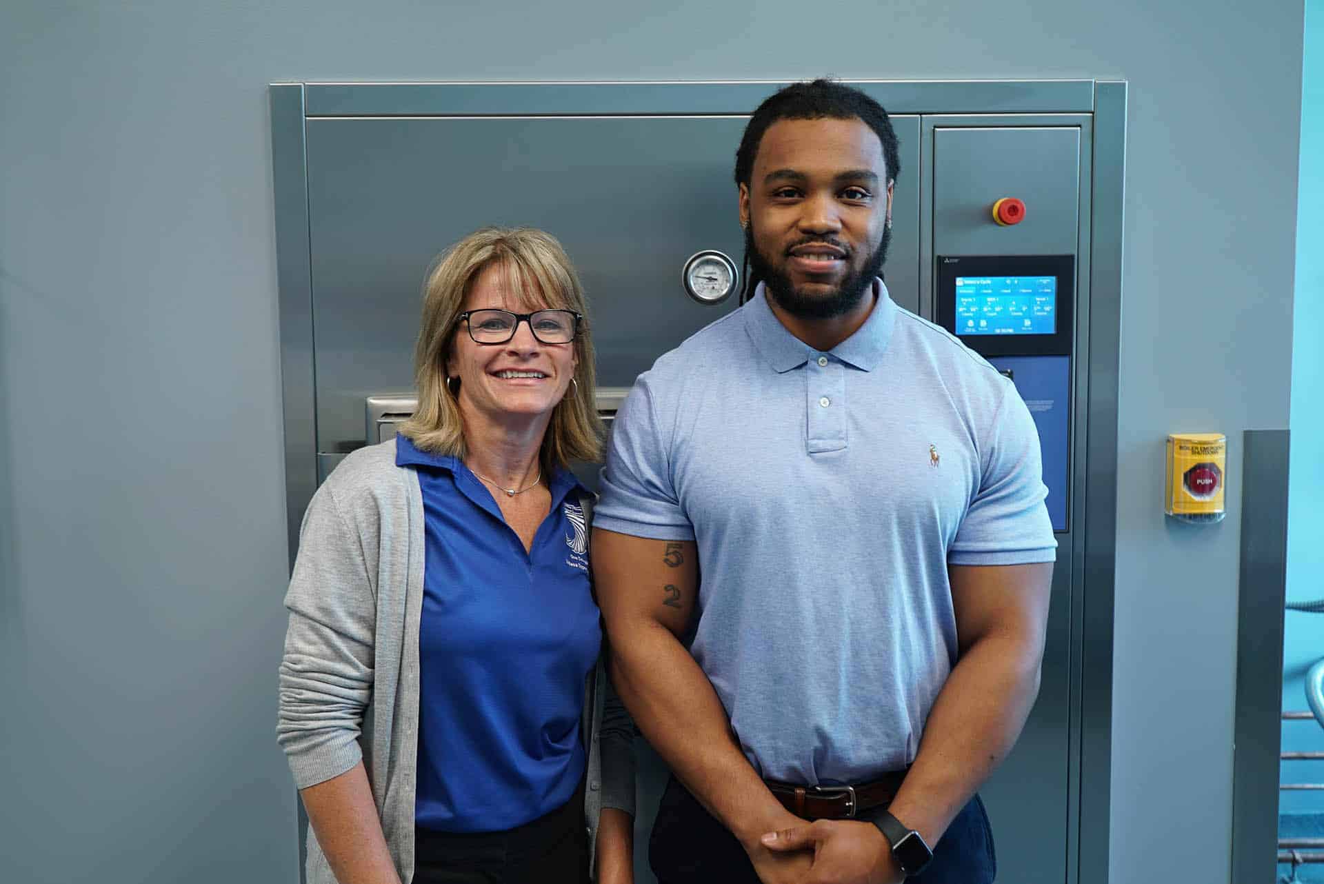 an instructor and student stand in front of machinery