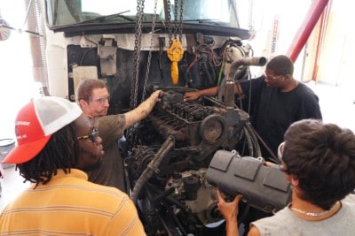 students work on a large Diesel engine