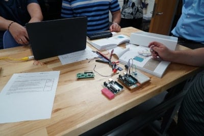 students at a table with laptops and circuit boards