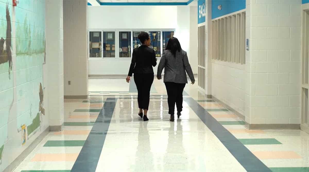two women walking away through School hallway