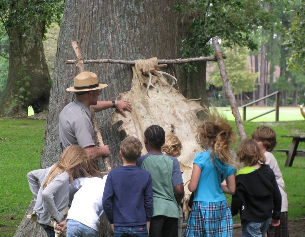 man pointing to animal skin in the woods