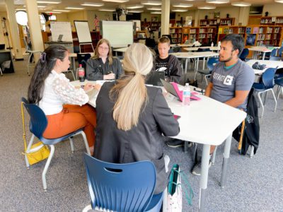 students sitting at round table with adult