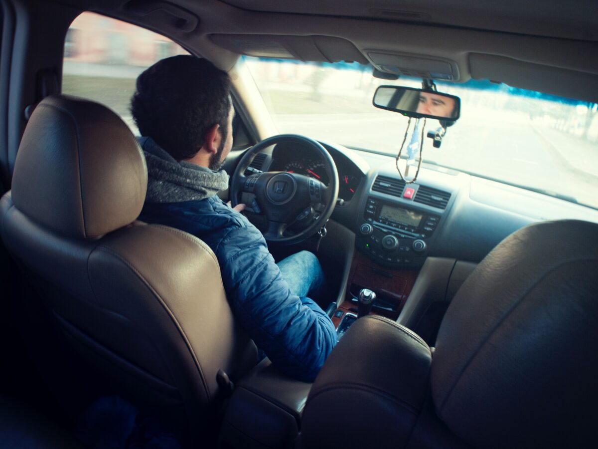 backseat view of a man driving a car a