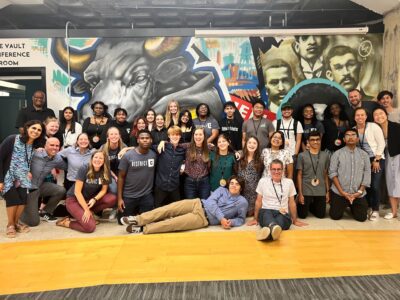 high school students posing for group phot in front of bull mural