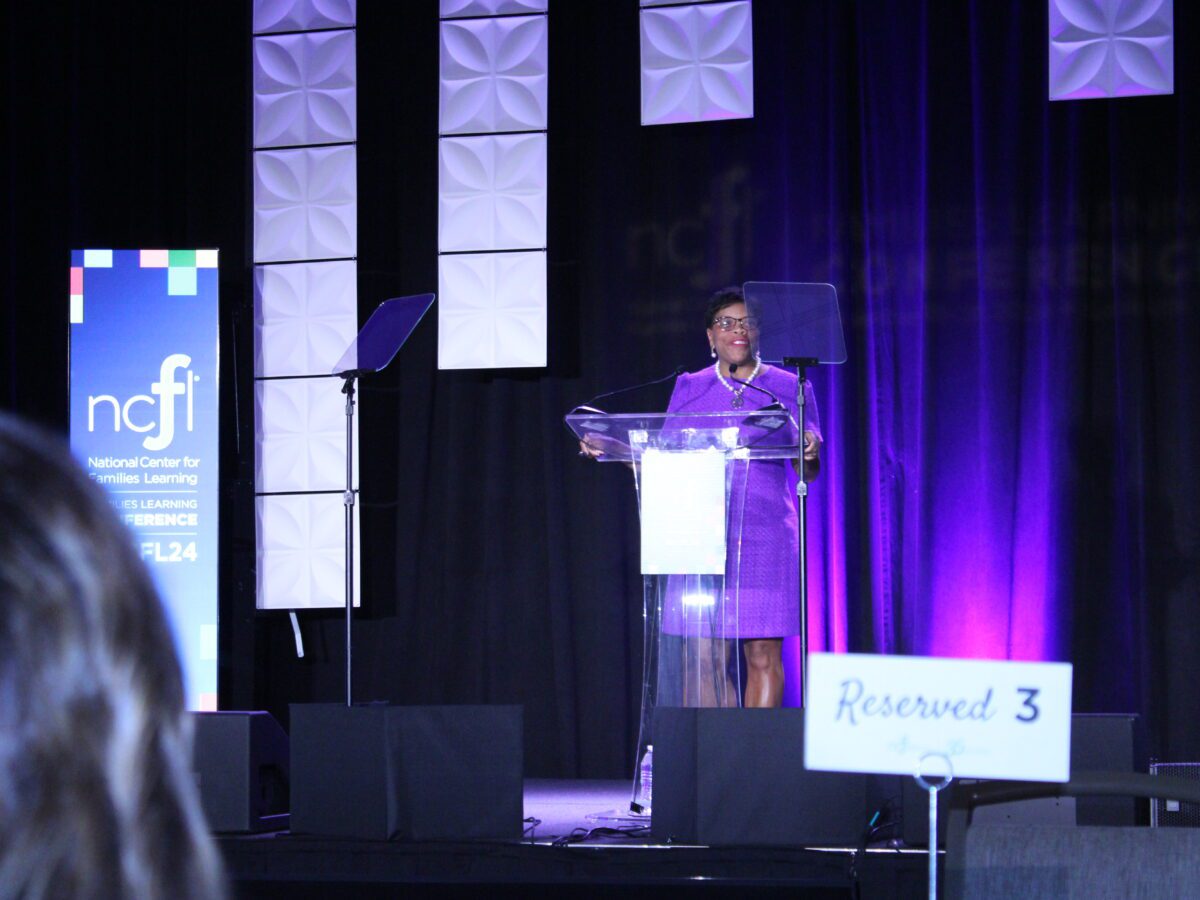 woman standing behind podium and infront of ncfl banner