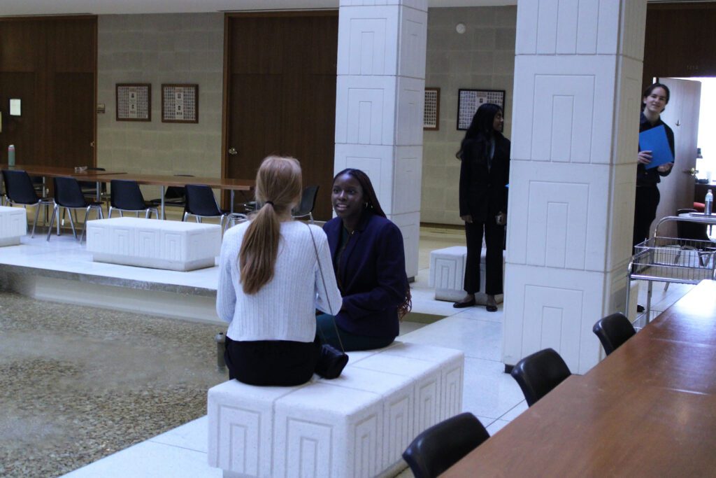students sit on white bench in wide open space