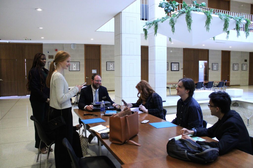 people sitting at brown table laughing and holding blue folders