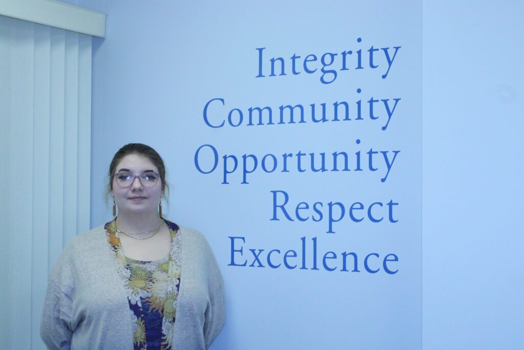 woman standing by words integrity, community, opportunity, respect, excellence