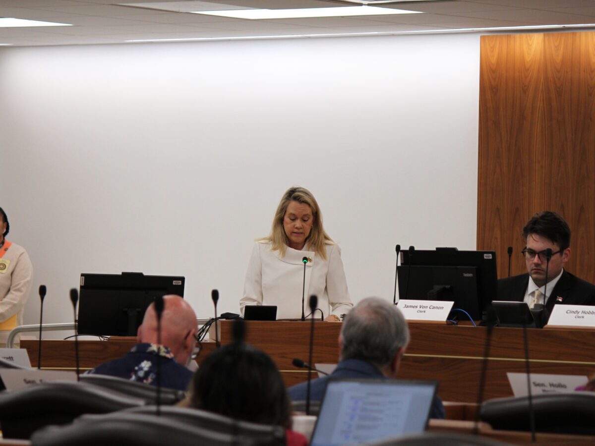 woman in white sweater in front of room at podium