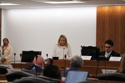 woman in white sweater in front of room at podium