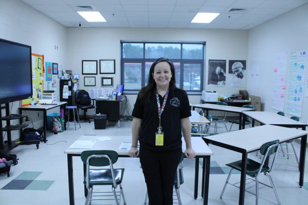 woman standing with her hands leaning on a desk behind her