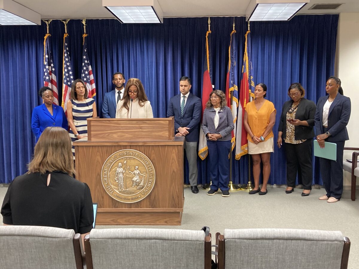 woman stands at a podium in front of North carolina and amaerican flag