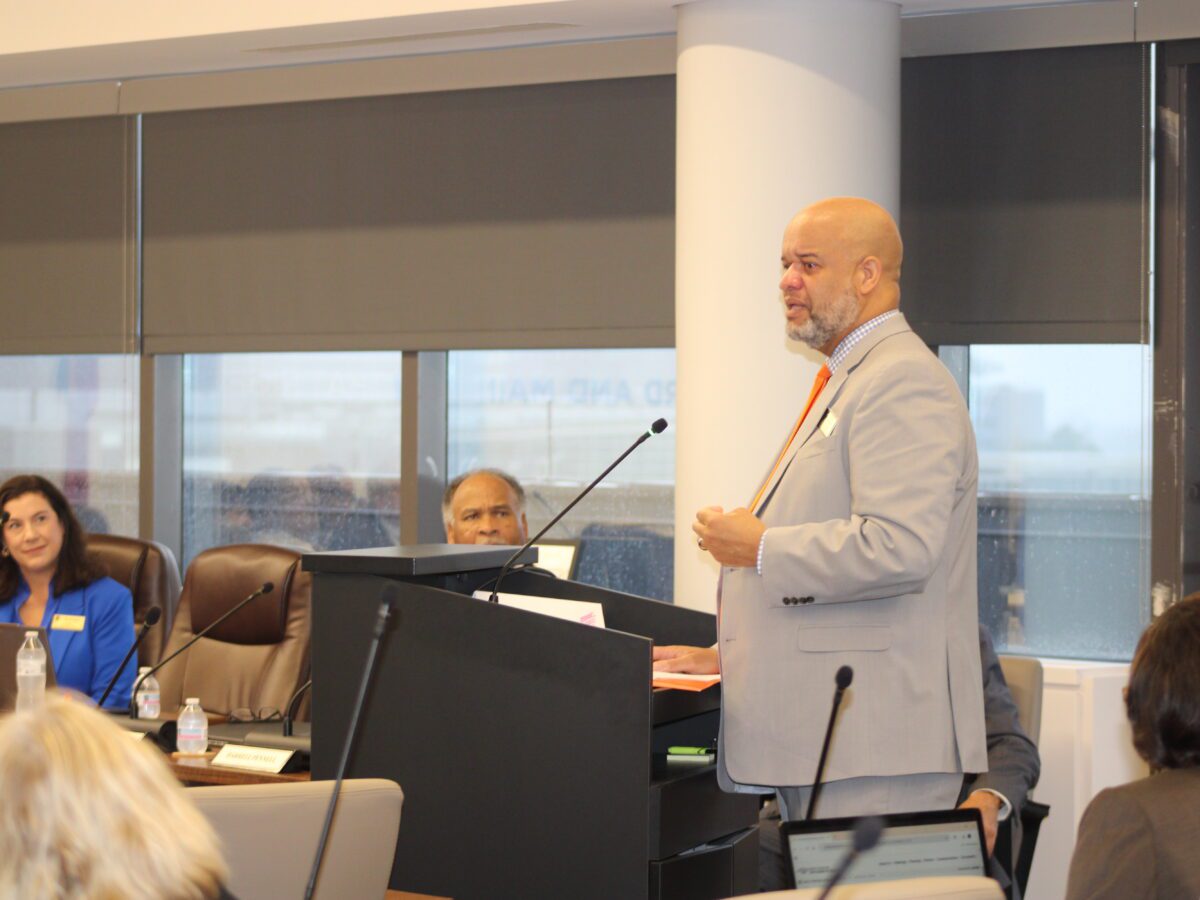 man speaking in boardroom at podium