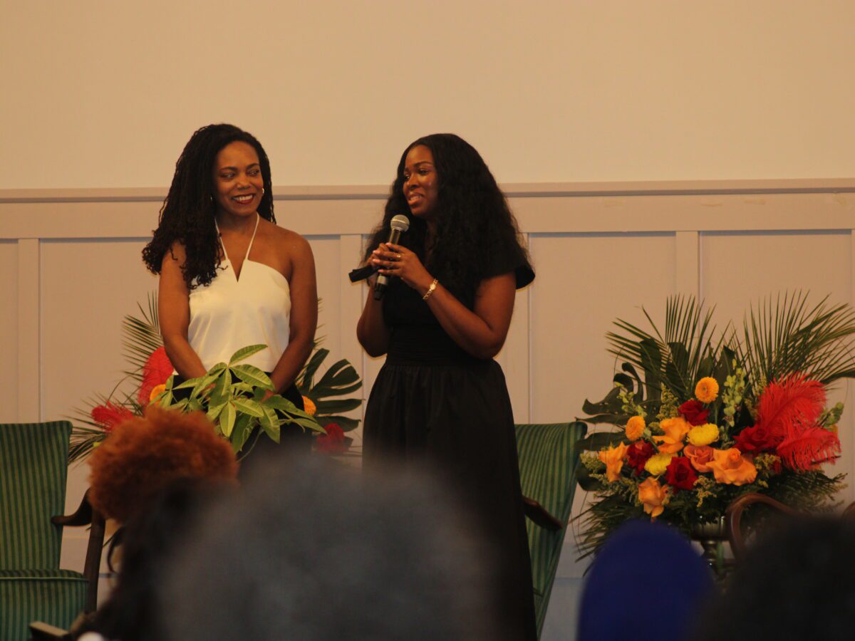 two women standing in front of a flower bouquet