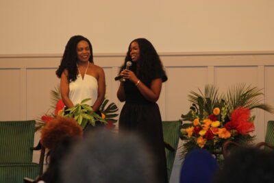 two women standing in front of a flower bouquet