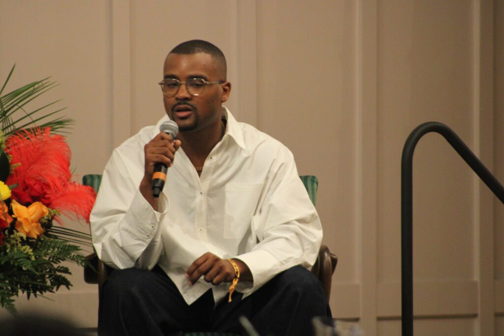 man in white shirt sitting holding microphone