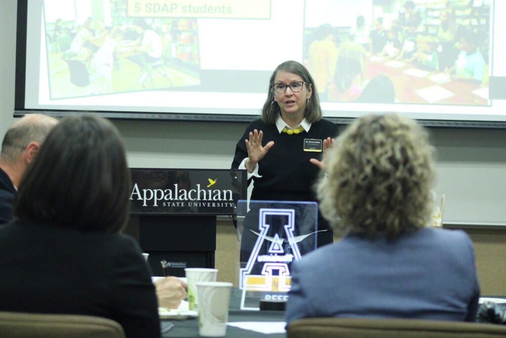 Woman speaking next to an app state podium while talking with her hands