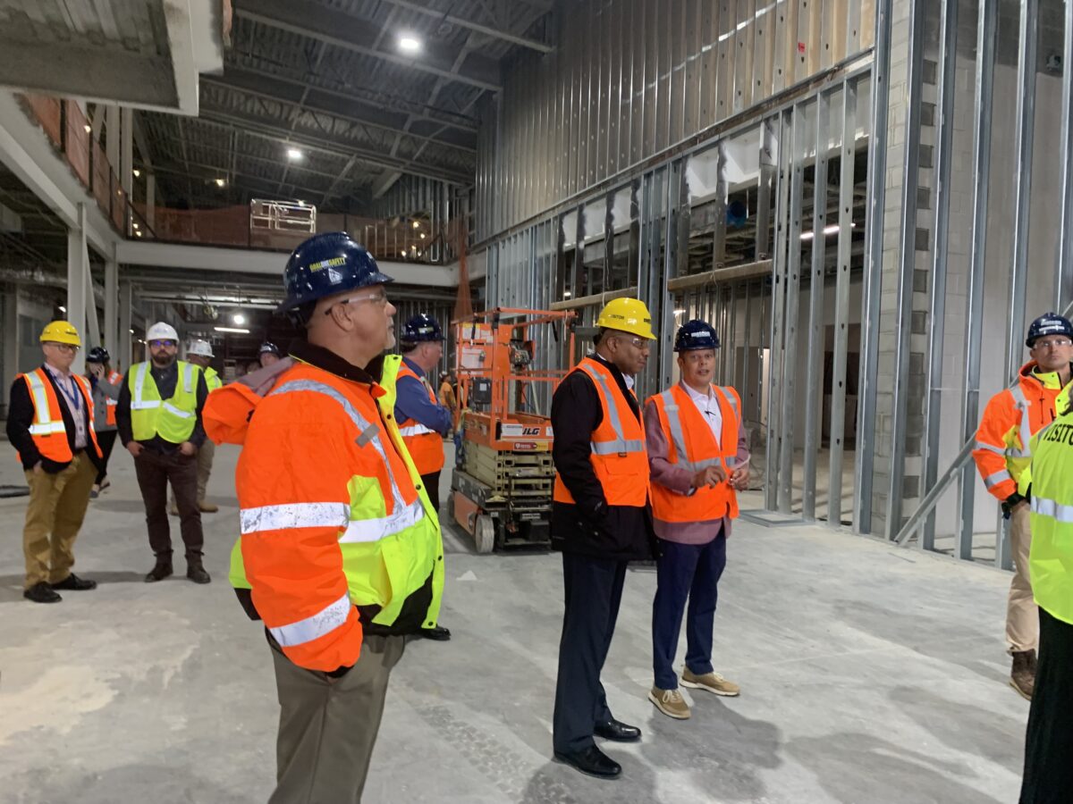 people in hard hats standing in front of a construction lift