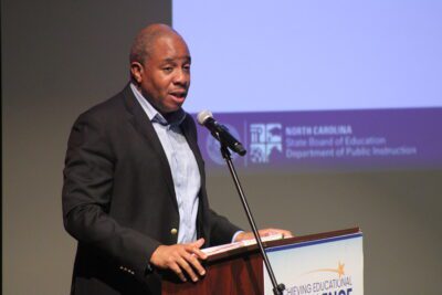 man standing at a podium leaning into a mic