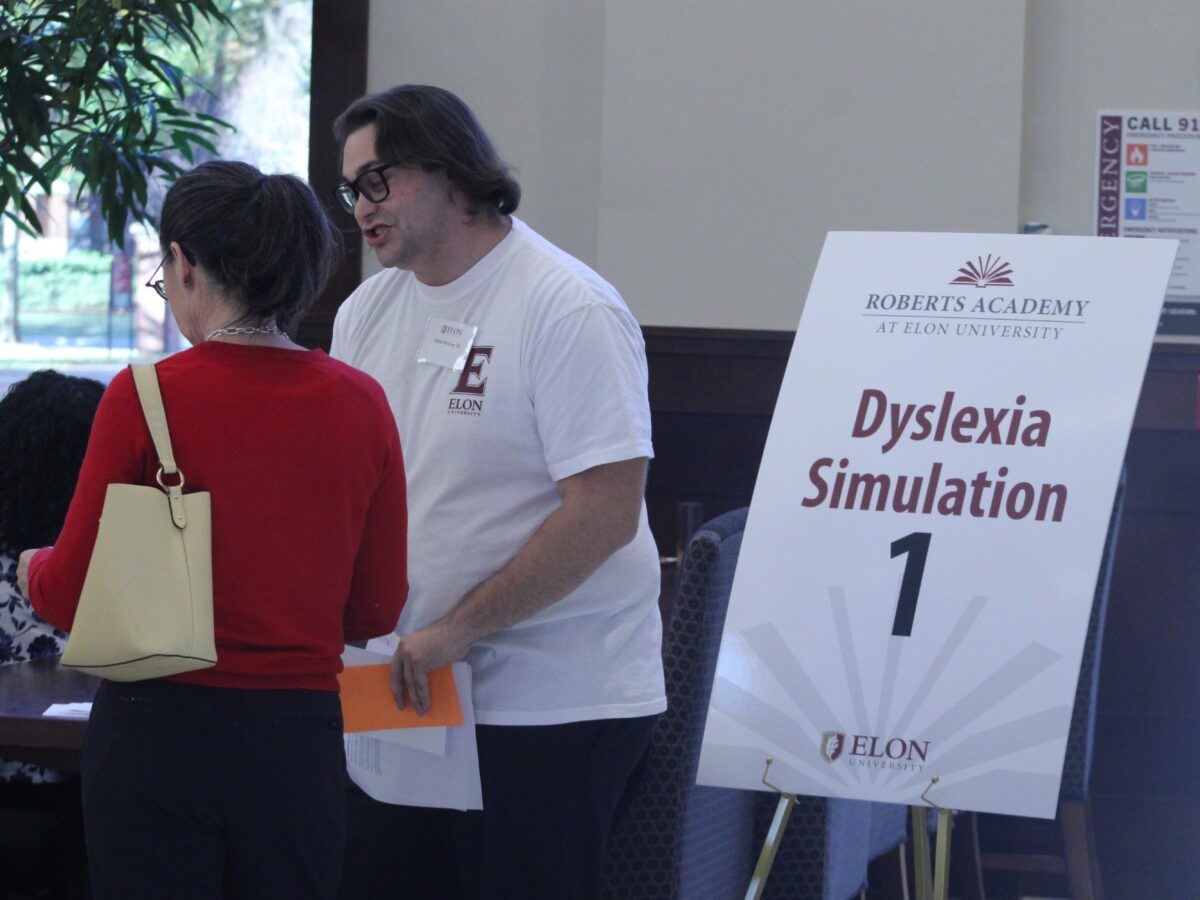 people standing in front of a table and sign that says "dyslexia simulation"