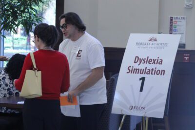 people standing in front of a table and sign that says "dyslexia simulation"