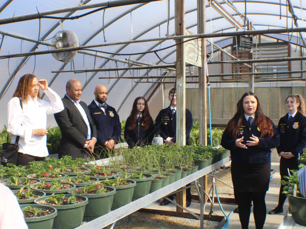 people standing with a table full of plants between them in a dome shaped greenhouse