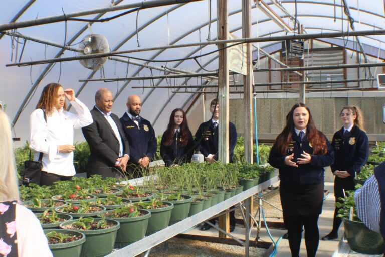 people standing with a table full of plants between them in a dome shaped greenhouse