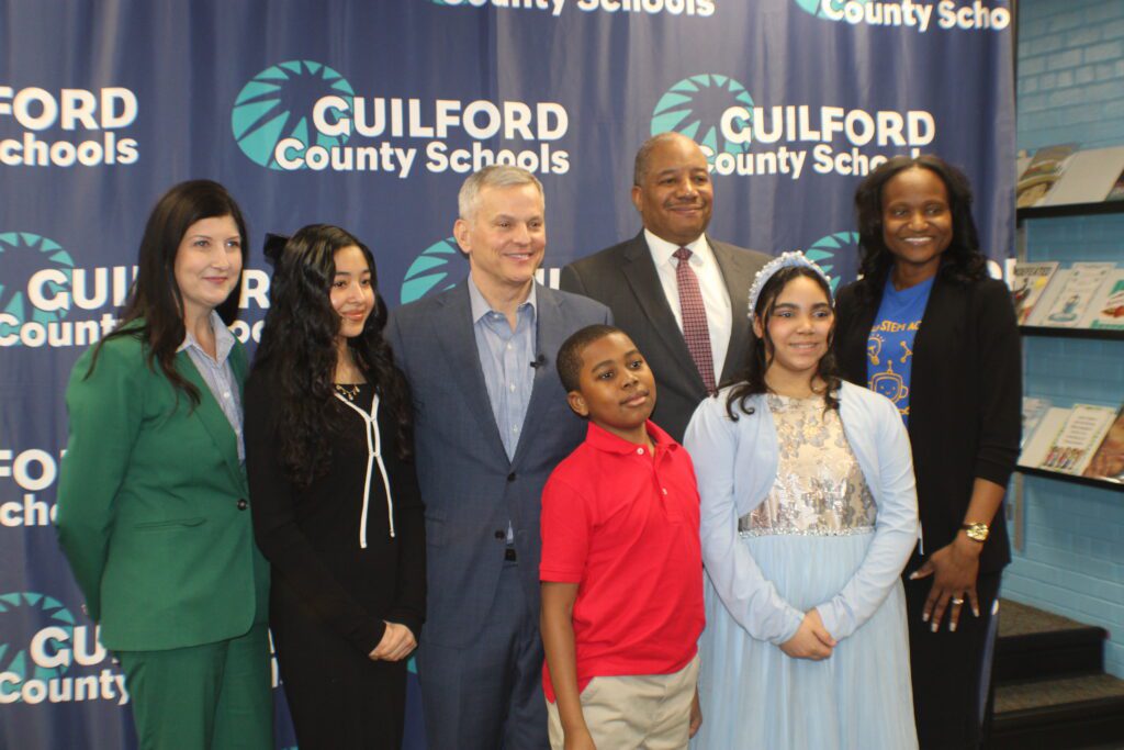 people posing in a group in front of a Guilford County Schools backdrop.