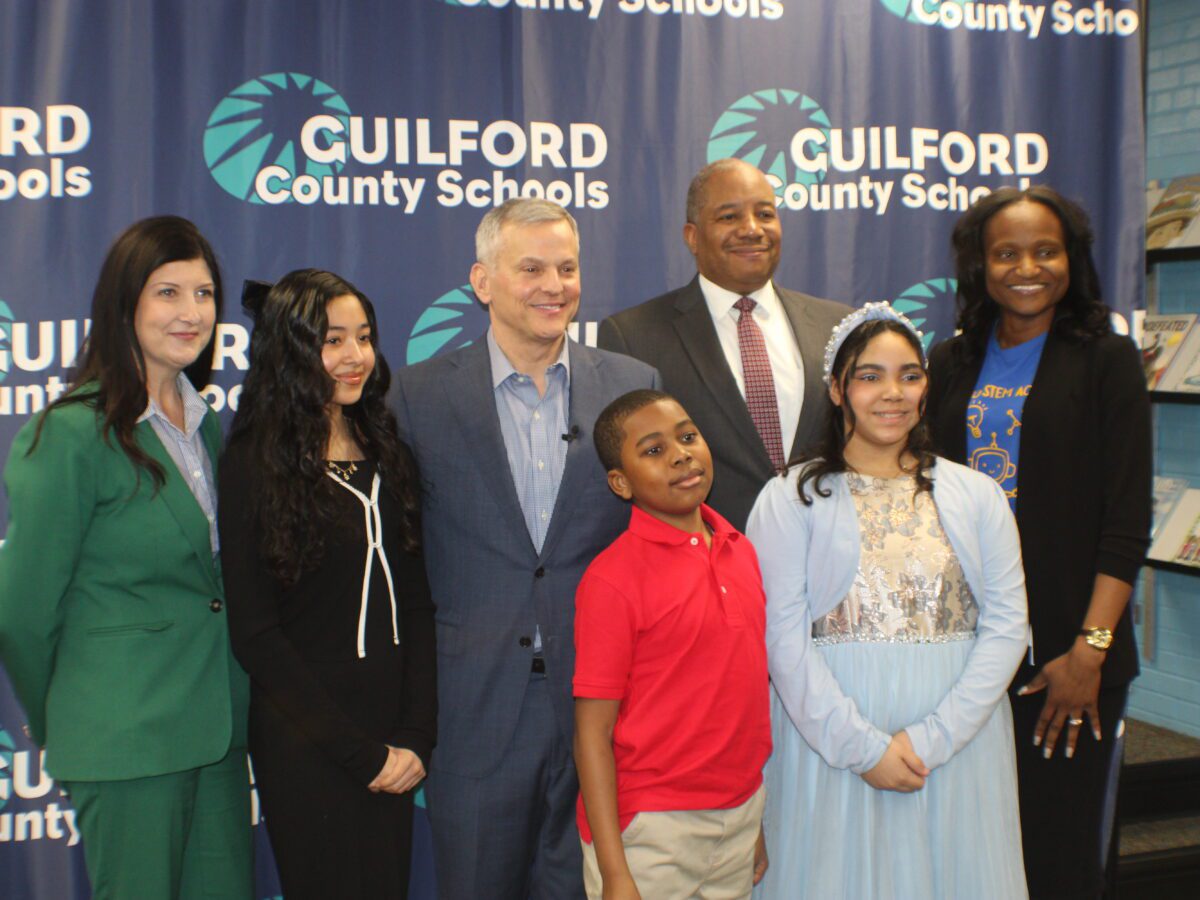people posing in a group in front of a Guilford County Schools backdrop.