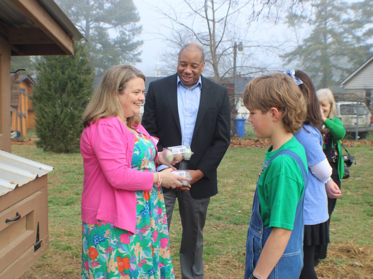 mo green standing with students and principal in front of chicken coup