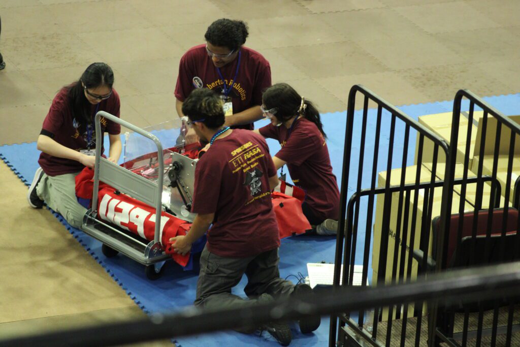 students on their knees circled around a robot