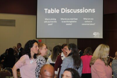 people standing and talking under a slideshow