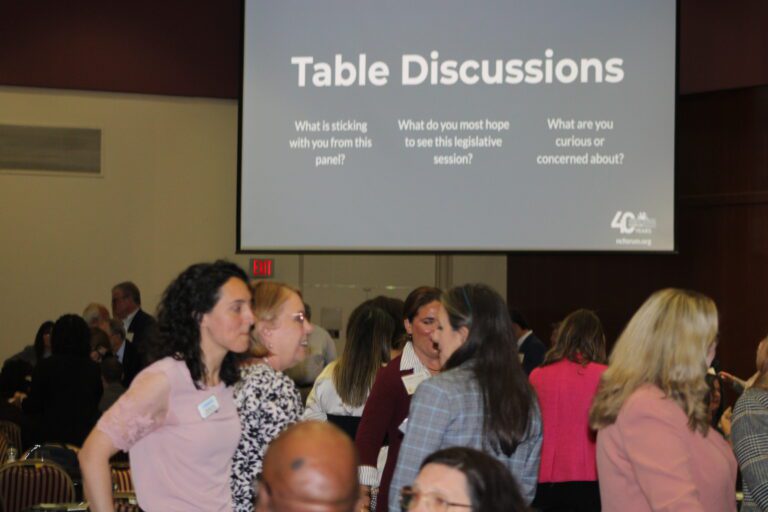 people standing and talking under a slideshow
