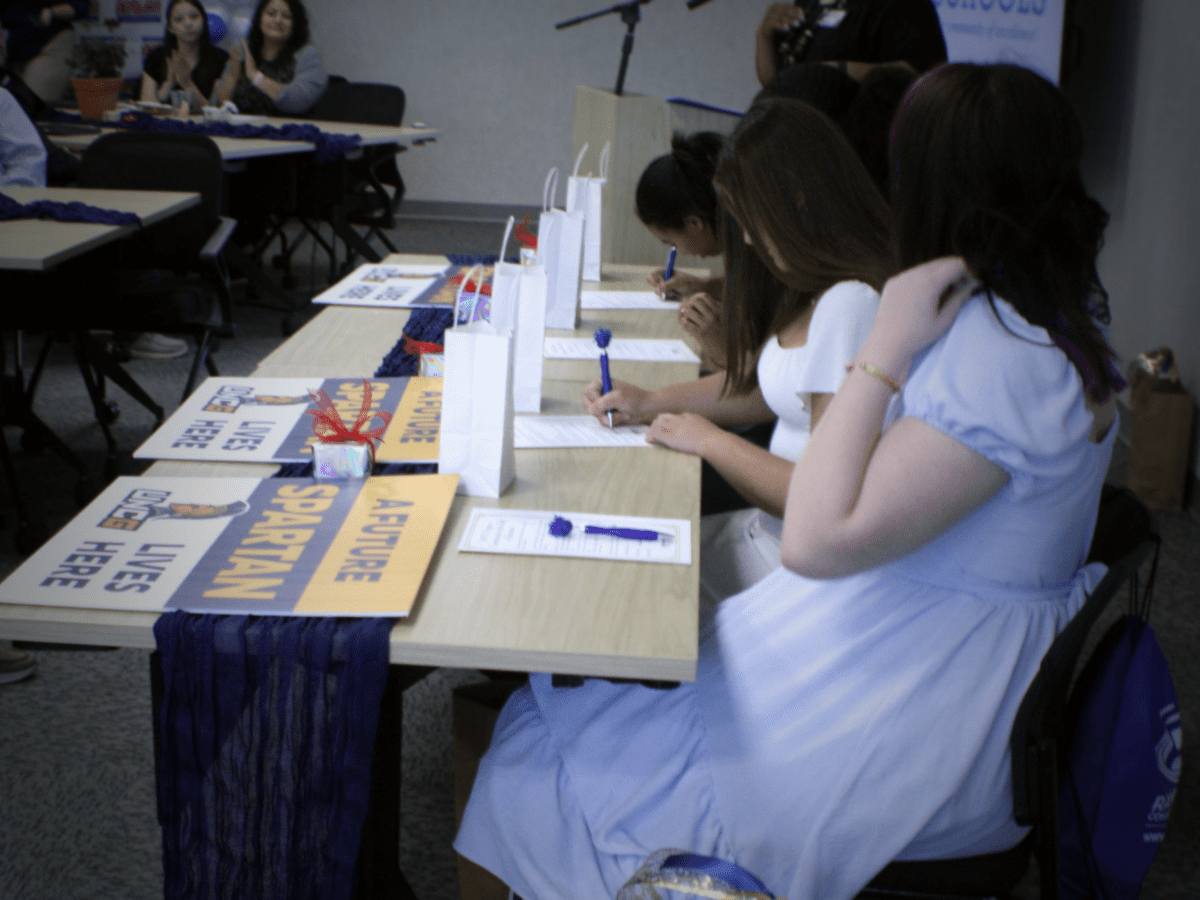 people sitting at a long table signing papers