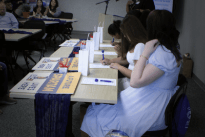 people sitting at a long table signing papers