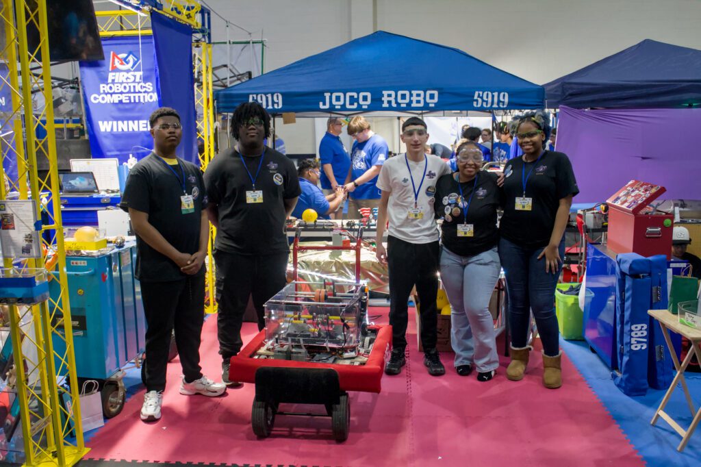 5 students standing around robot on a flatbed