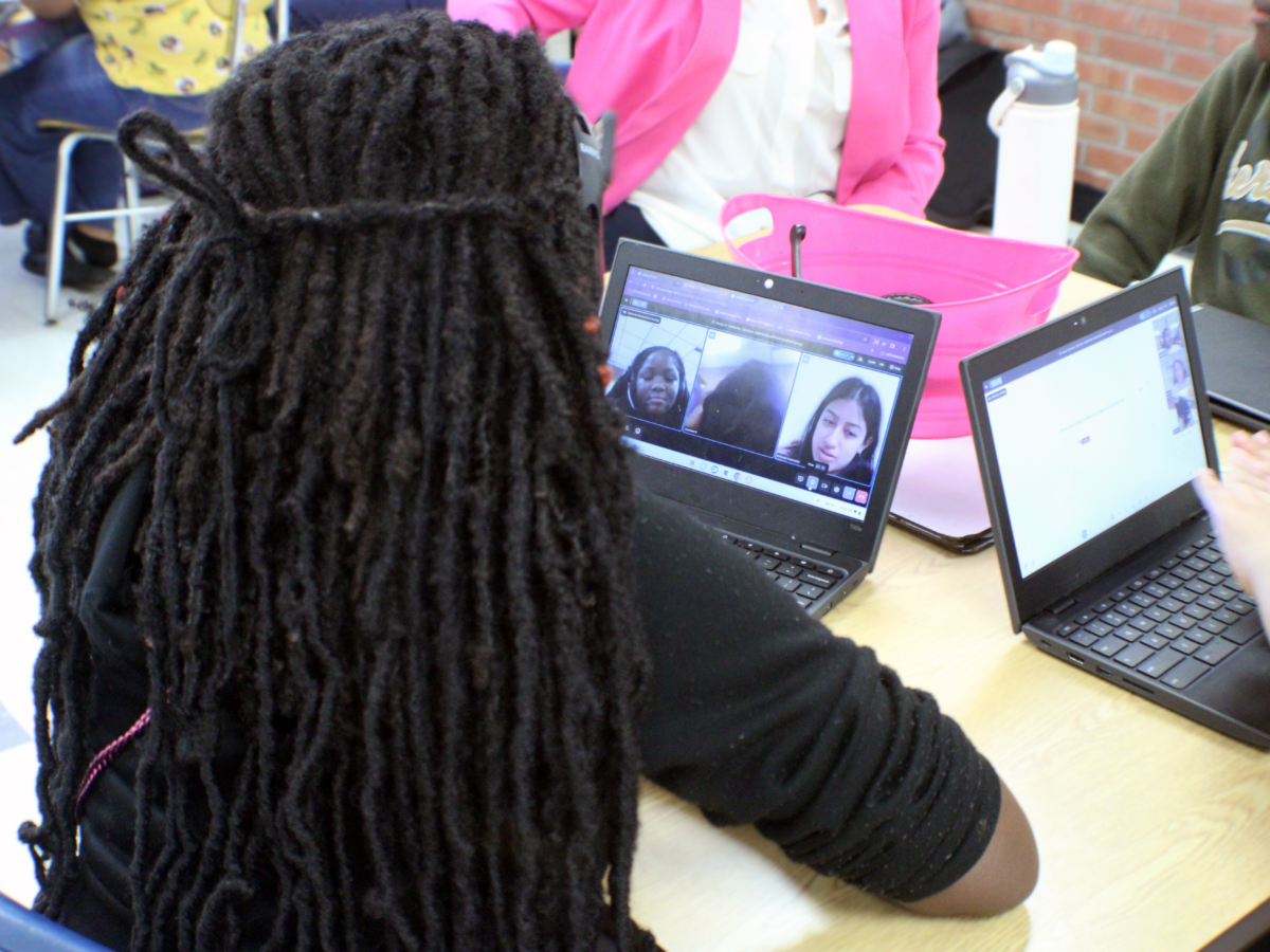 student on a video call sitting at desk with four other people