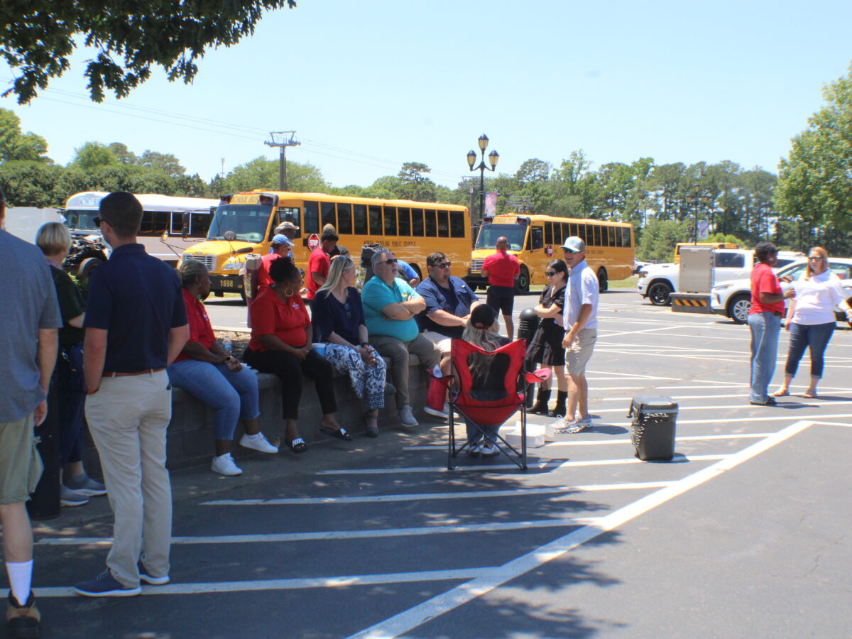 people sitting in front of school buses.